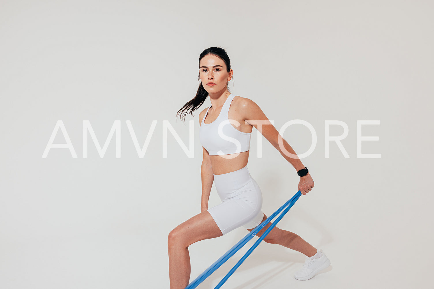 Young female athlete in white sports clothes using a resistance band to train arm