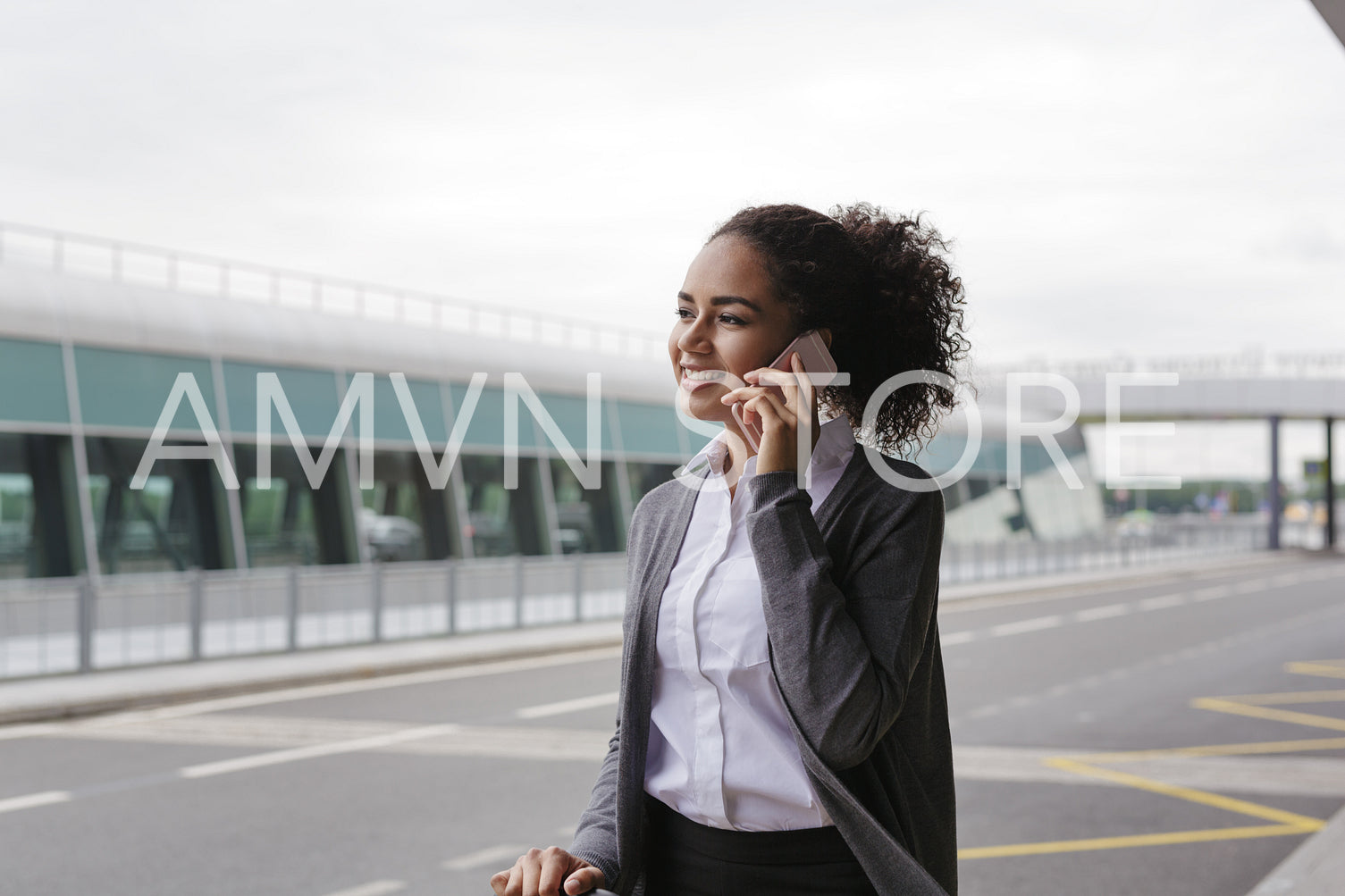 Young smiling woman using smartphone, standing outdoors	