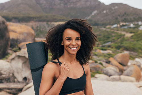 Portrait of a young smiling woman holding a mat against beautifu