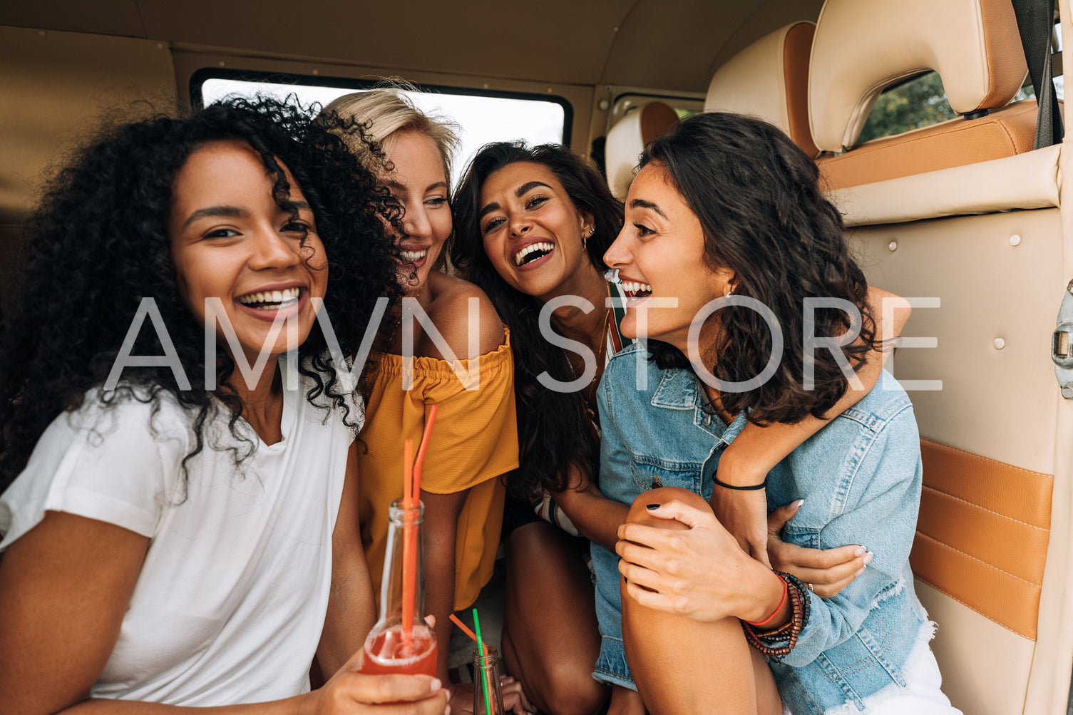 Multi-ethnic group of young women laughing while sitting in a minivan