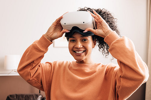 Happy mixed race woman looking at camera wearing VR goggles