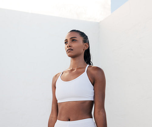 Slim confident sportswoman relaxing during exercises. Portrait of a fit female in white fitness attire.