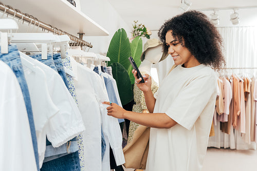 Side view of young woman photographing clothes in shop