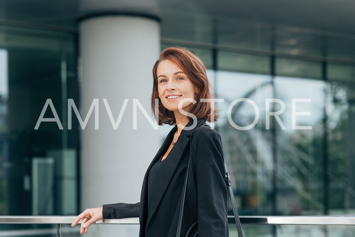 Smiling woman with ginger hair in black formal clothes outdoors