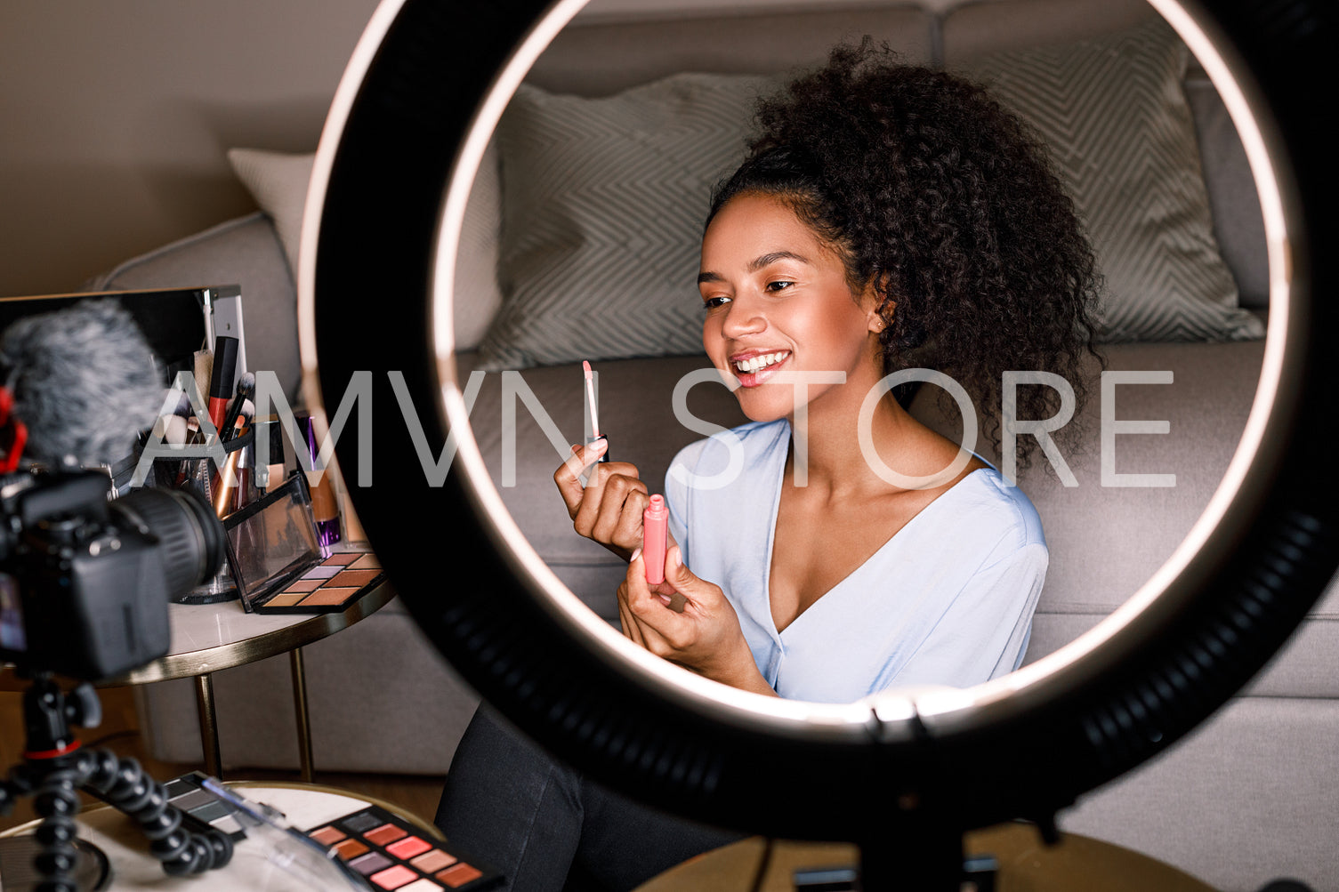 Smiling vlogger showing lipstick brush while recording a video