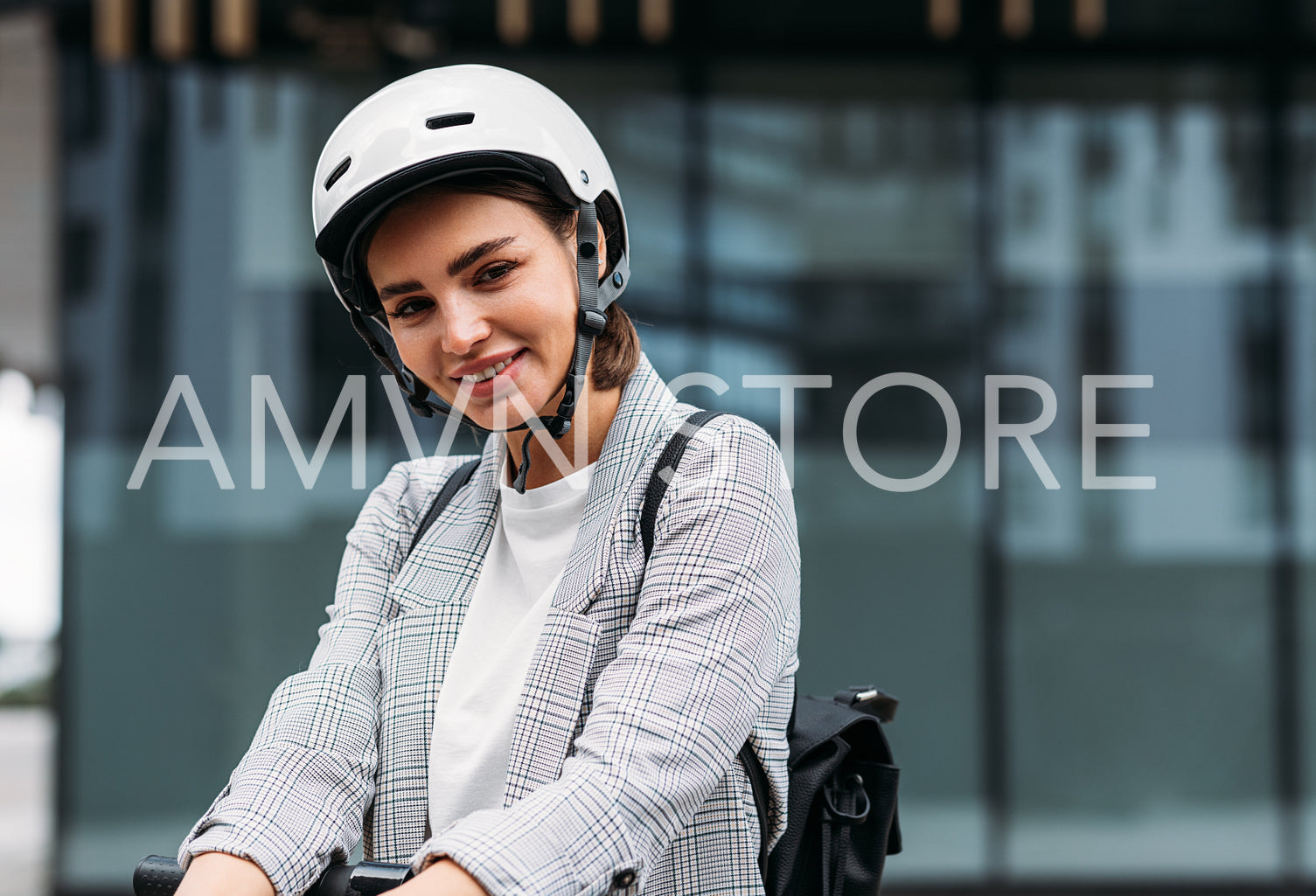 Beautiful smiling businesswoman in cycling helmet lean on handlebar of electric scooter looking at camera