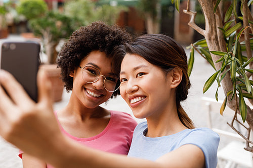 Two happy women taking selfie in outdoor restaurant