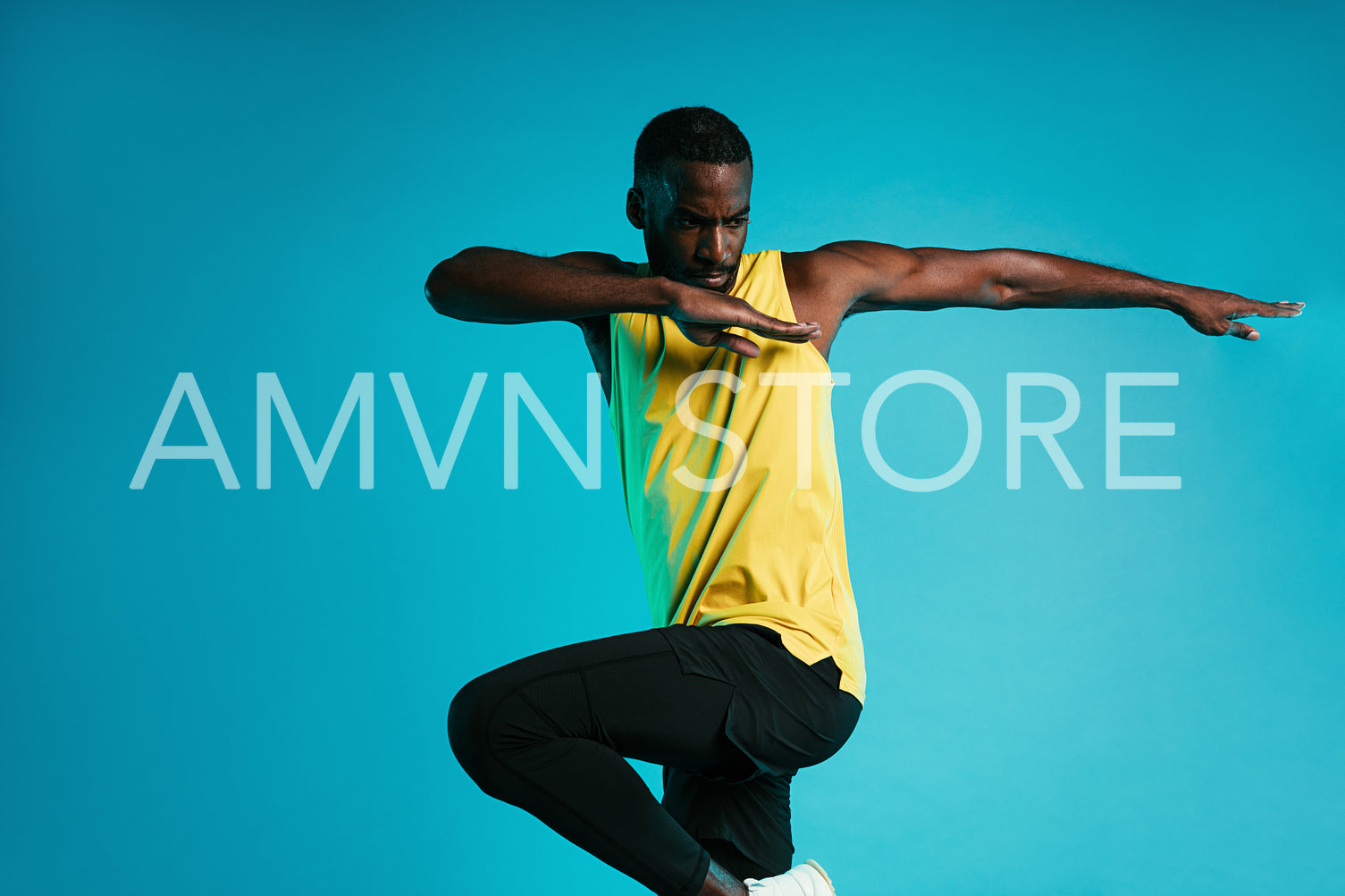 Young sportsman doing exercises against a blue background. Athlete warming up his body before fitness training.