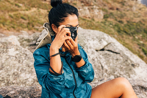 Young female taking photographs of the landscape with a film cam