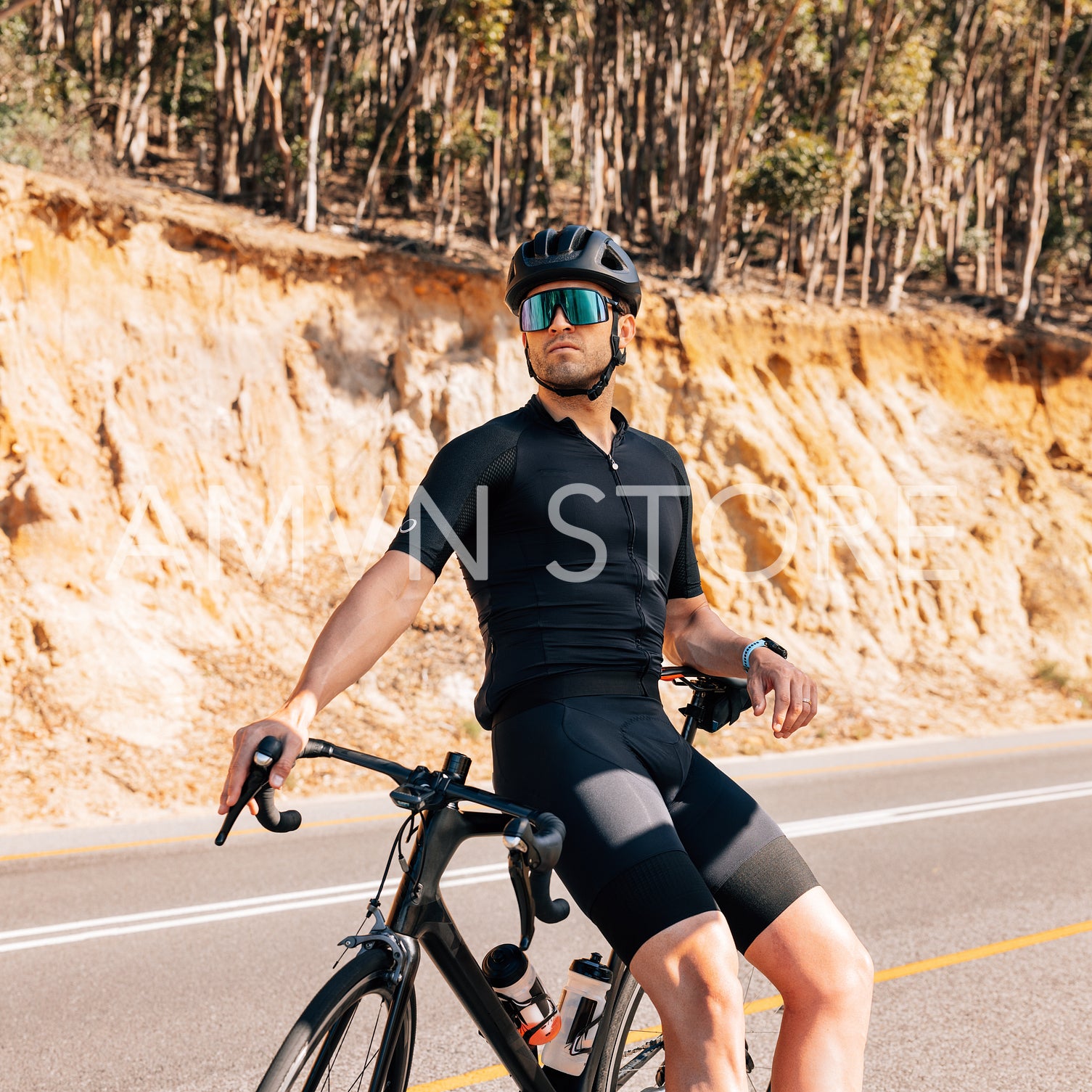 Male cyclist relaxing after an intense ride. Profesional rider resting outdoors sitting on a road bike.