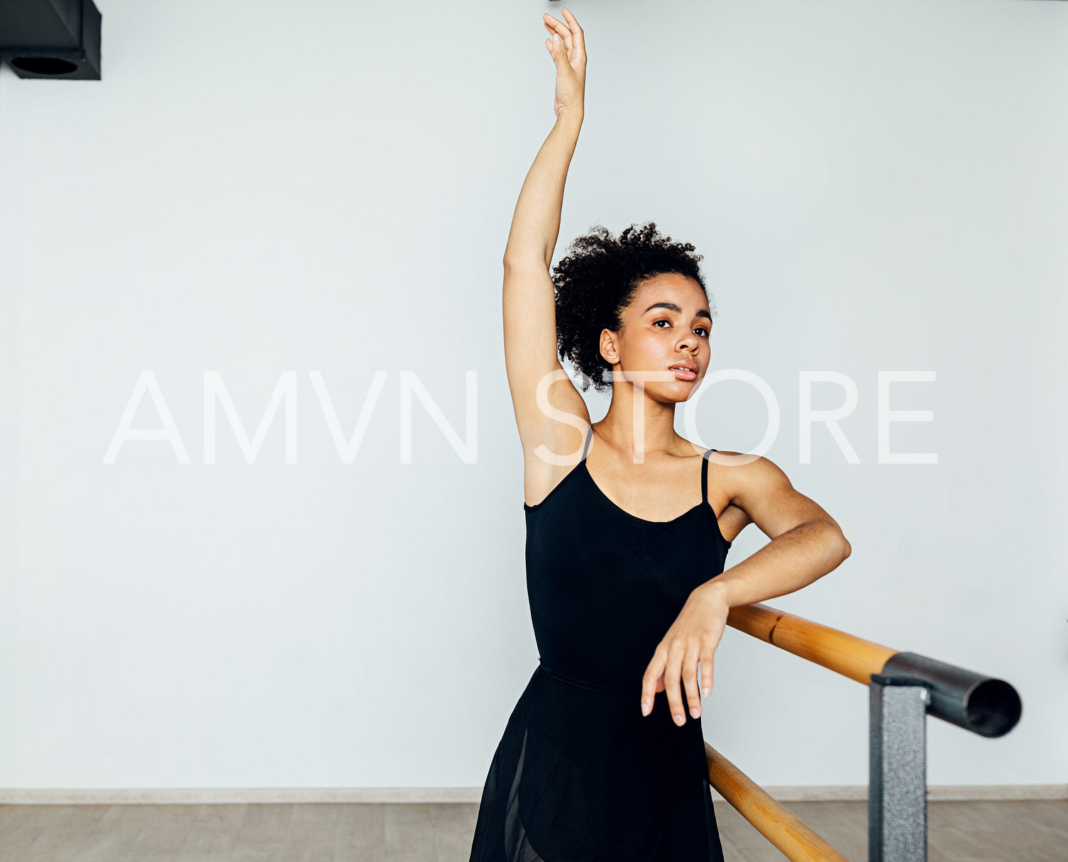 Professional ballet dancer practicing at barre in small studio	