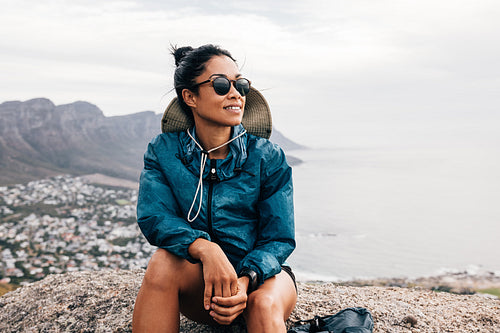 Young woman hiker enjoying the view while sitting on a mountain