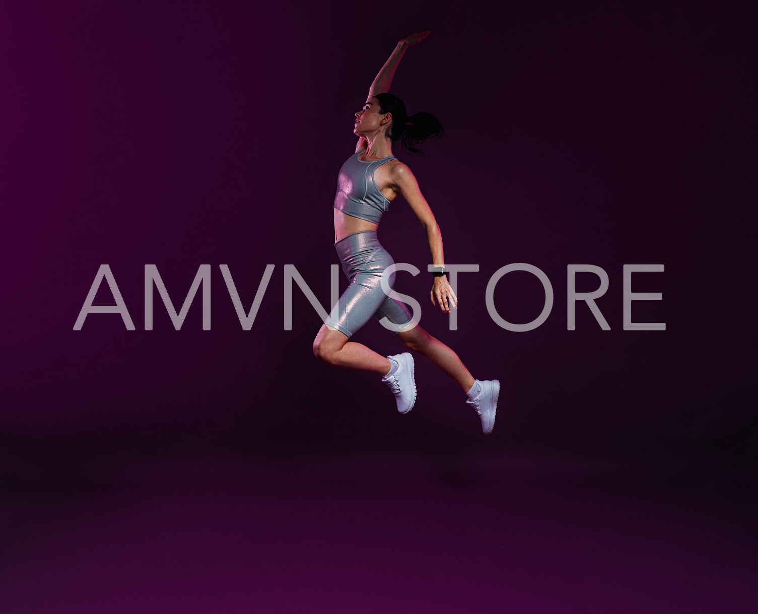 Full length of young female athlete jumping in the air over magenta background