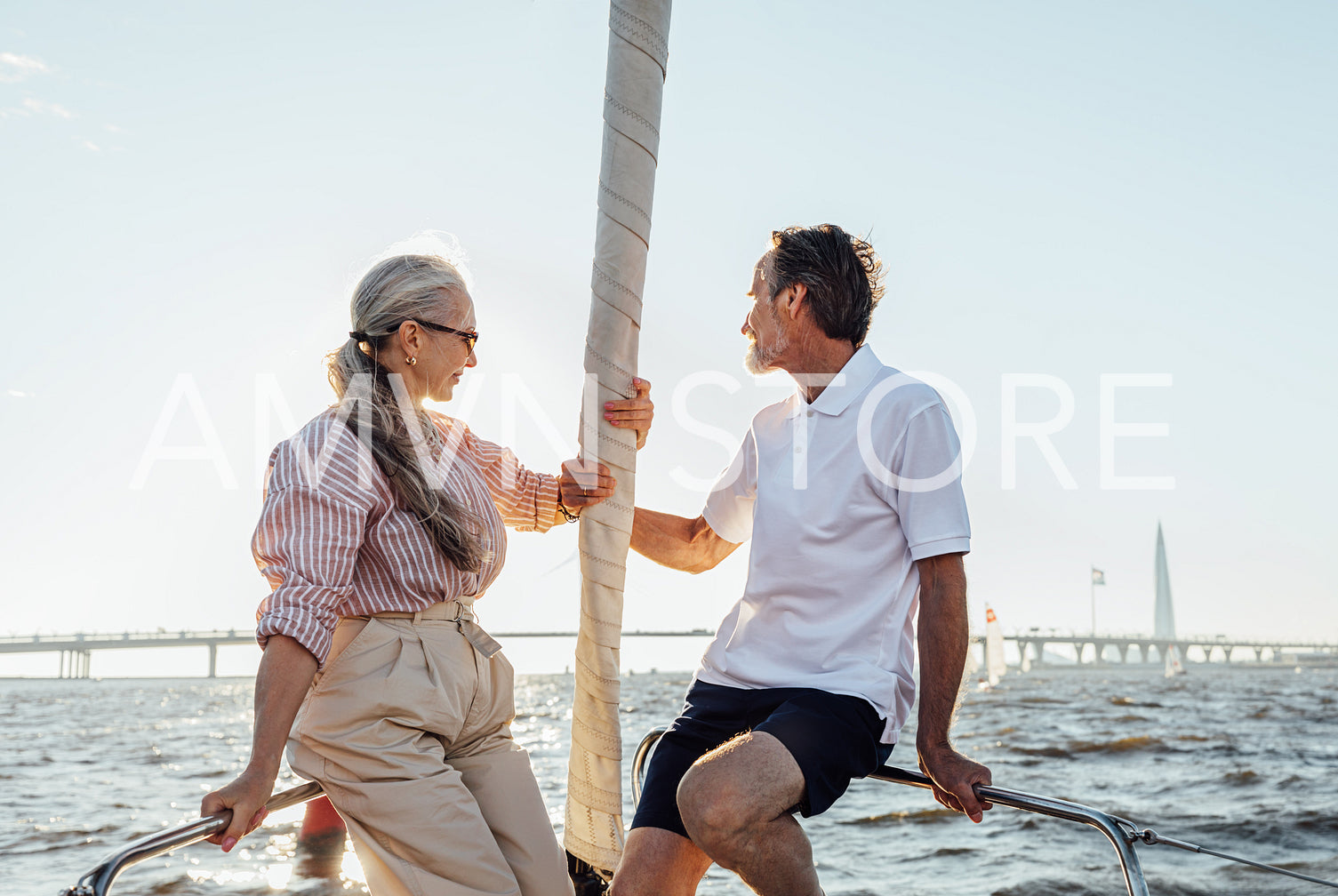 Elderly people sitting on sailboat bow and looking into distance	