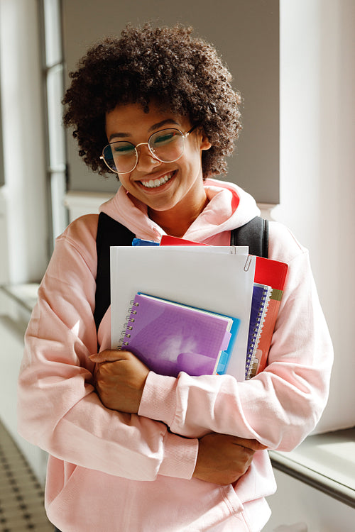 Portrait of a happy college student standing with books