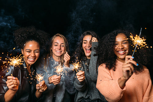 Group of young female friends having fun, raised hands up with sparklers