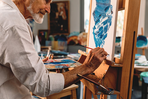 Close up of a senior artist drawing on canvas in studio