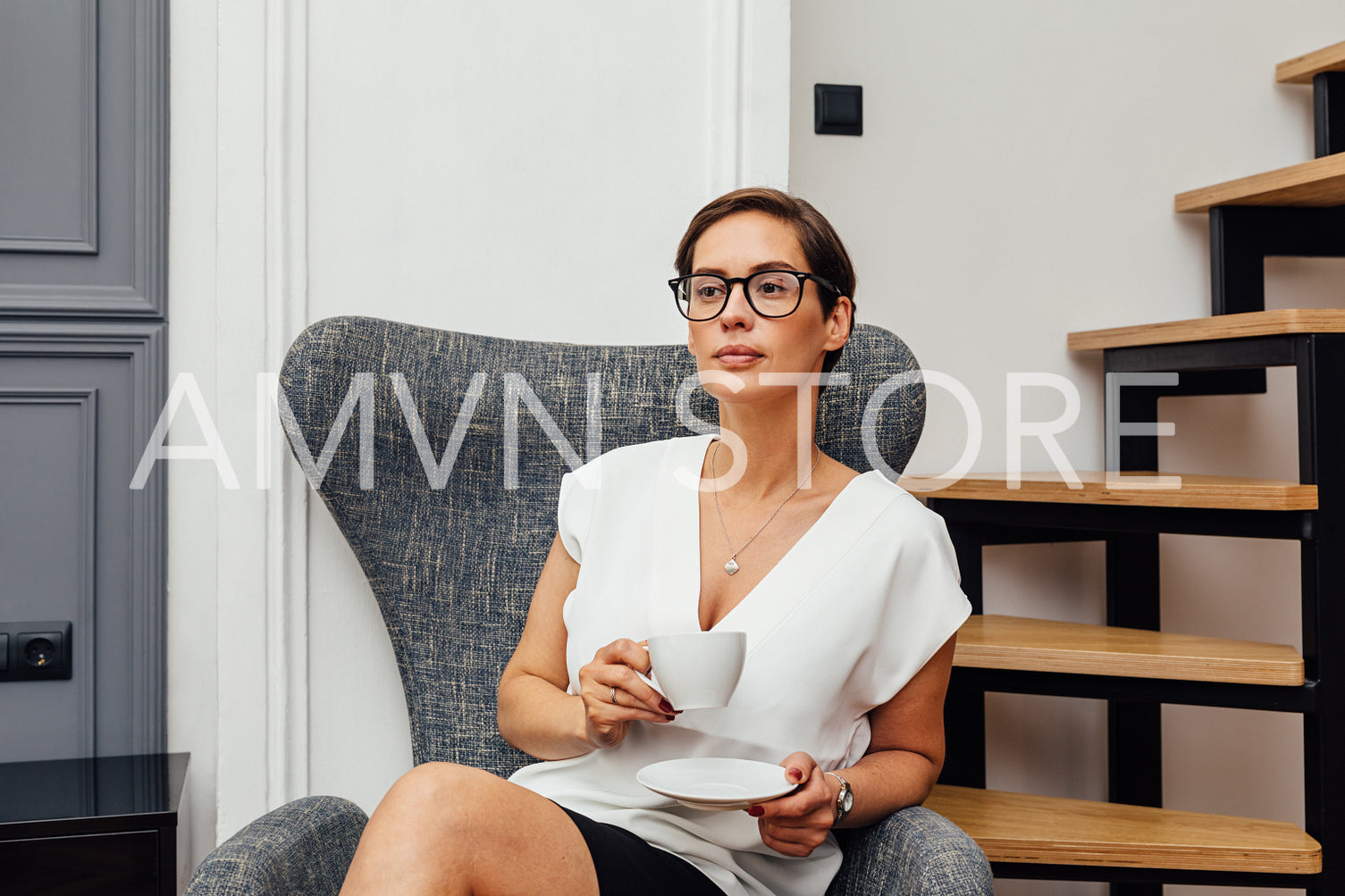 Beautiful mid adult woman drinking coffee in her apartment and looking away	