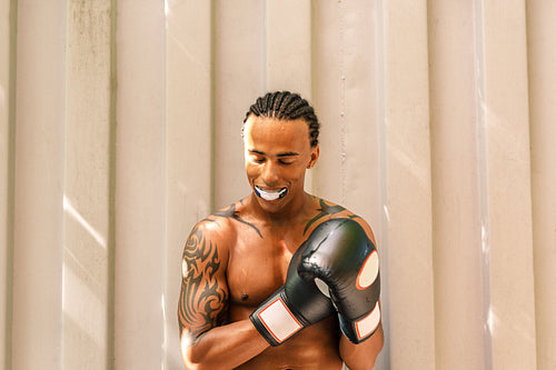 Male boxer with mouth guard outdoors. Tired and sweaty athlete with boxer gloves resting after training.