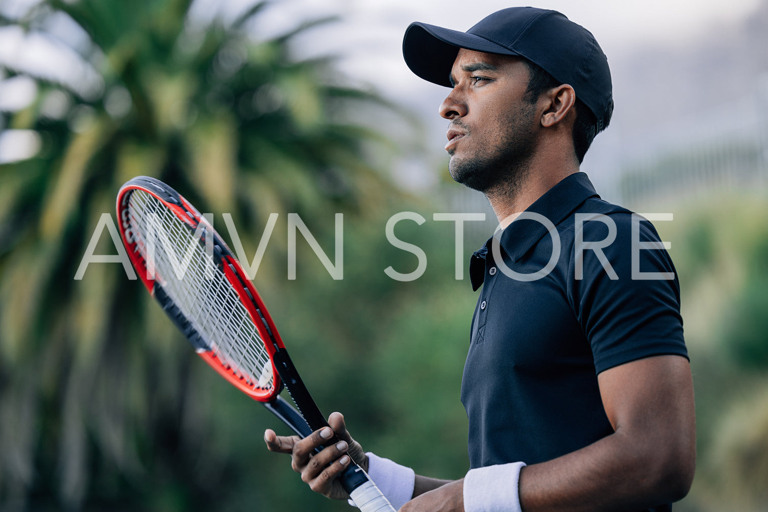 Side view of a young tennis player with racket looking away