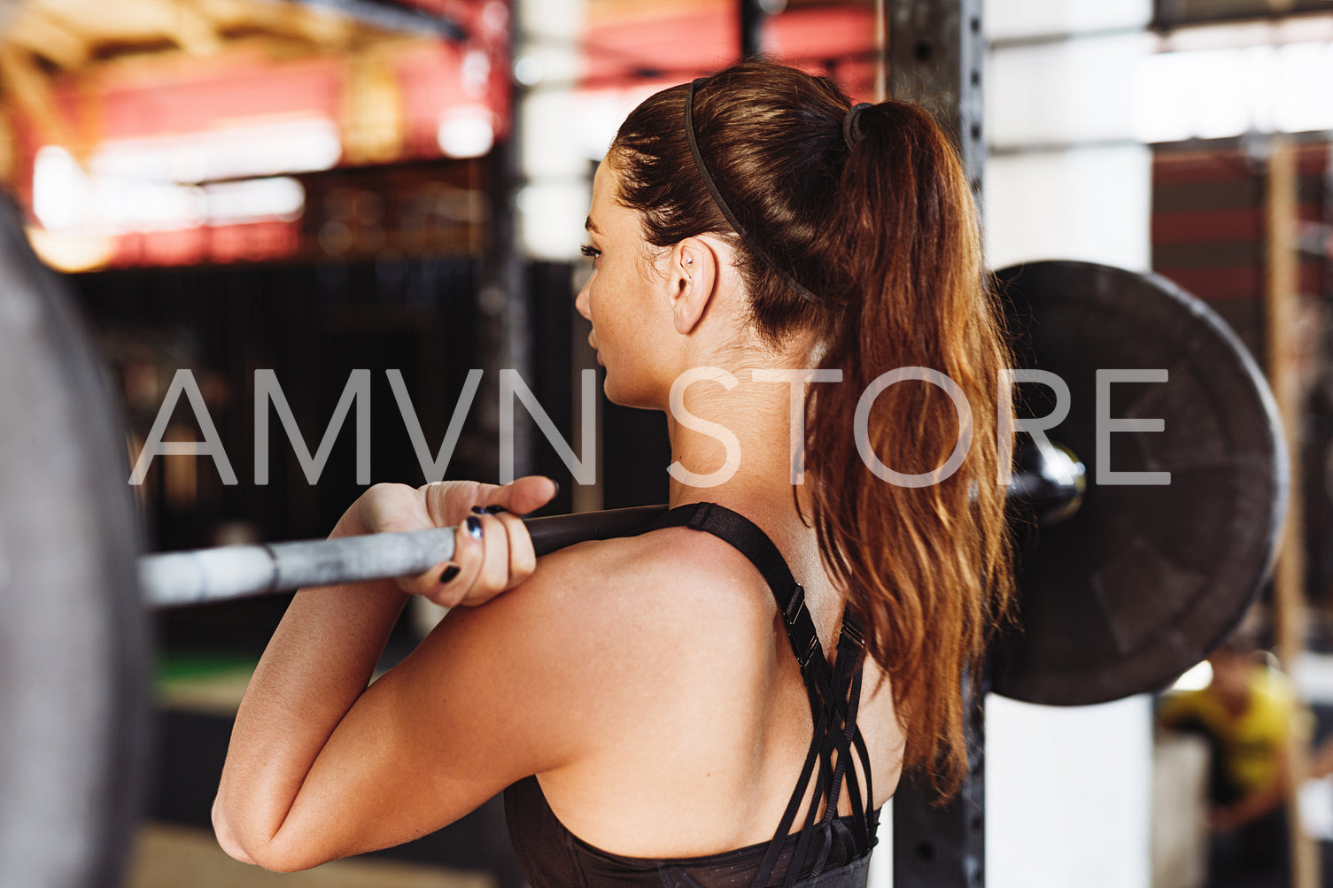 Back view of young sporty woman getting ready for working out with heavy weights	