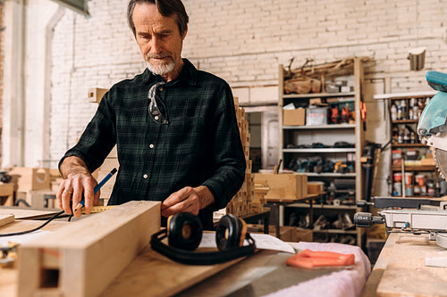 Male carpenter taking measurement of wood at workshop