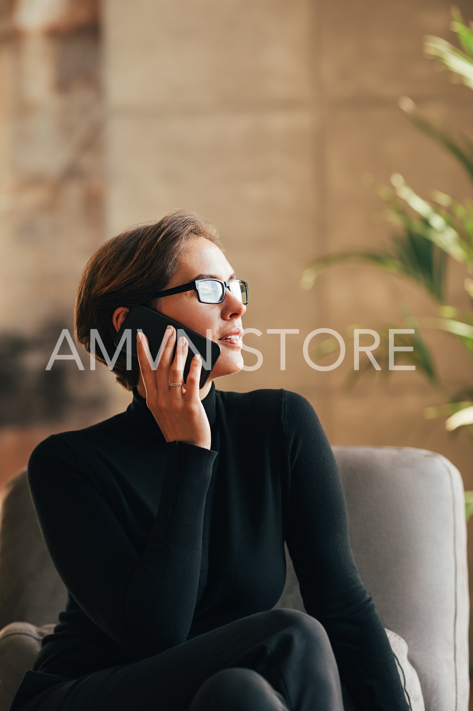 Businesswoman in eyeglasses wearing black formal clothes talking on mobile phone