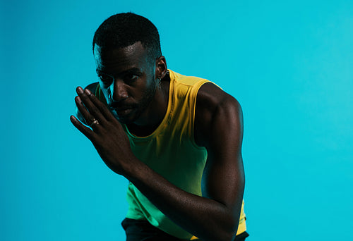 Close up of an African American athlete sprinting against blue background