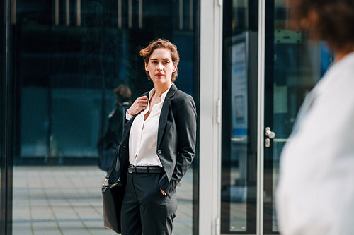 Young entrepreneur standing in front of an office building and looking away