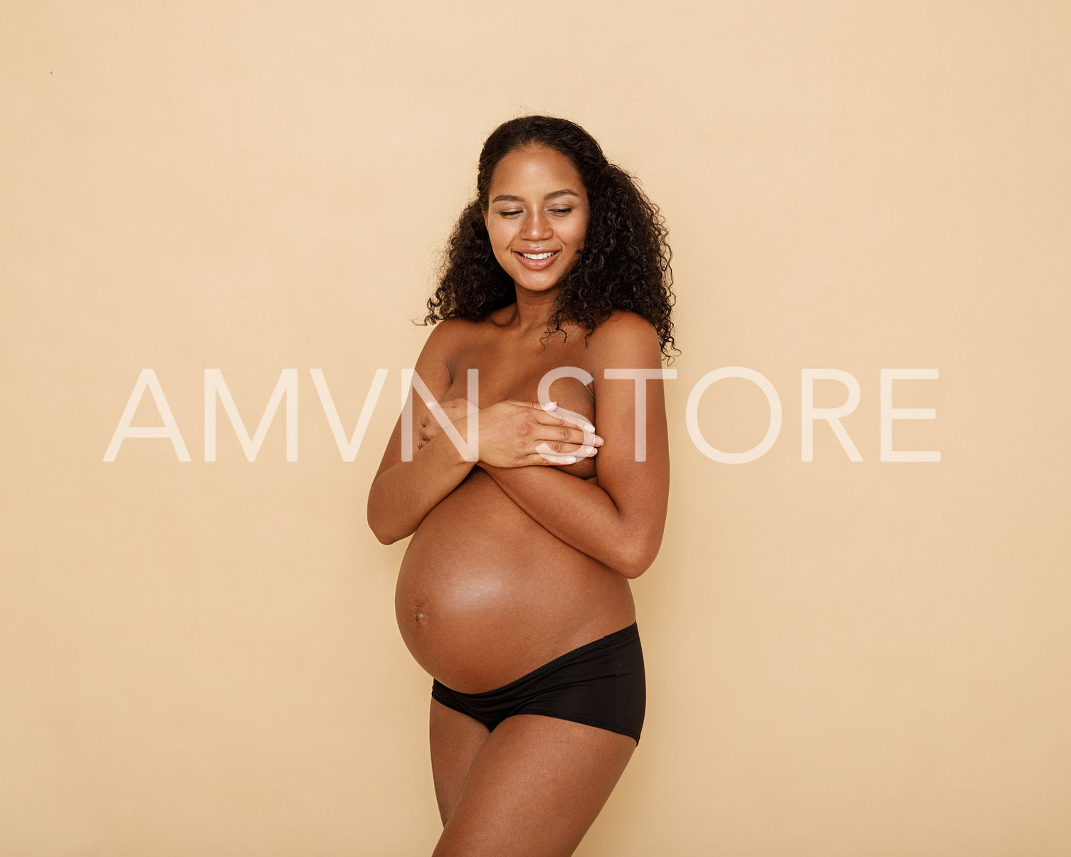 Studio portrait of a bare pregnant woman posing in studio with eyes closed	