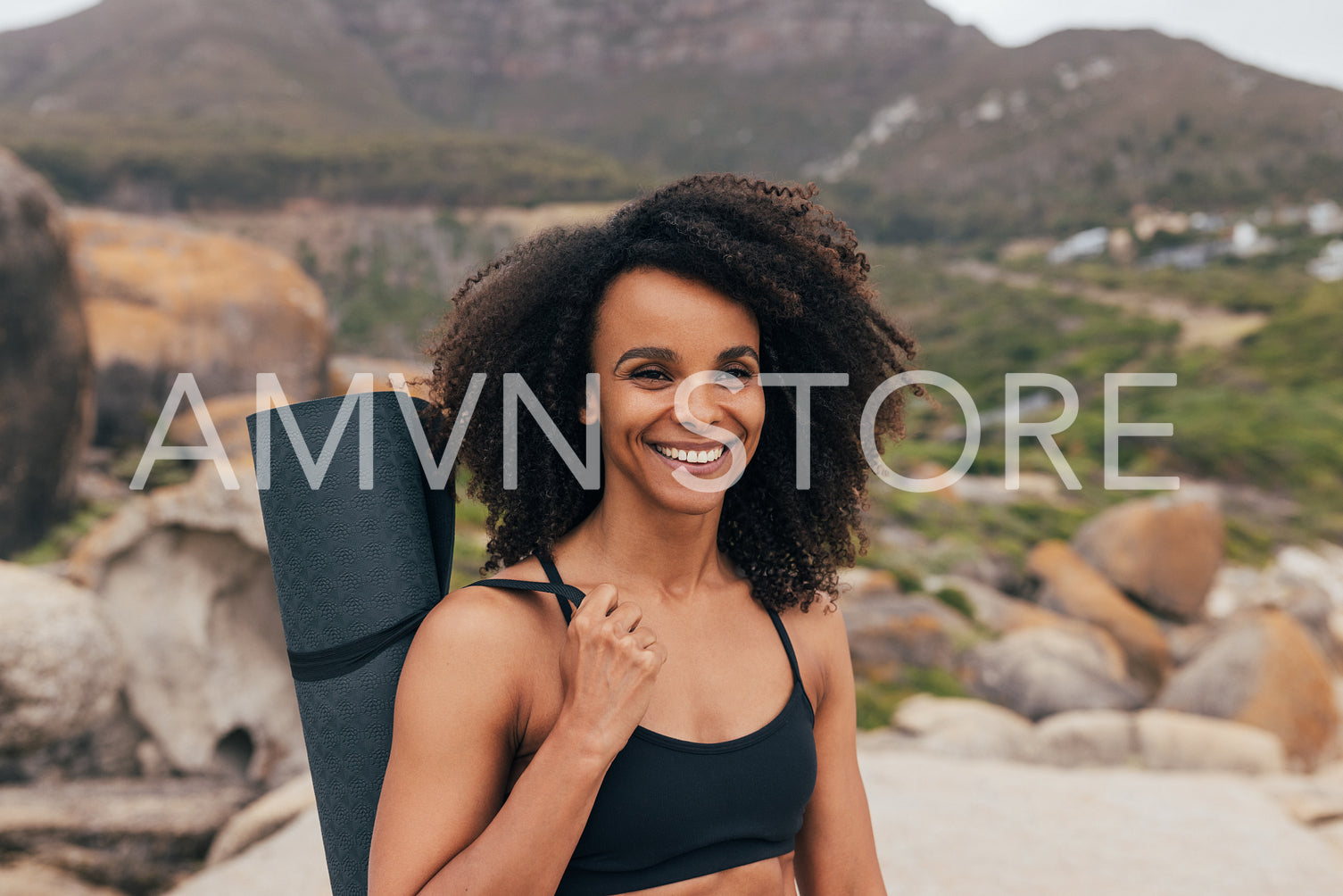 Portrait of a young smiling woman holding a mat against beautifu