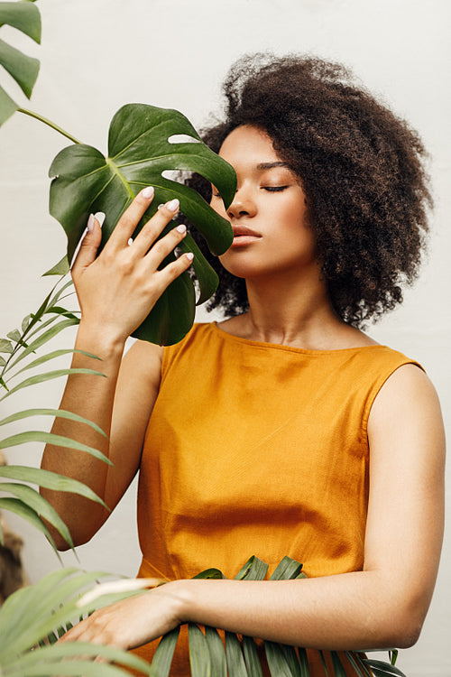 Woman with close eyes holding a monstera leaf