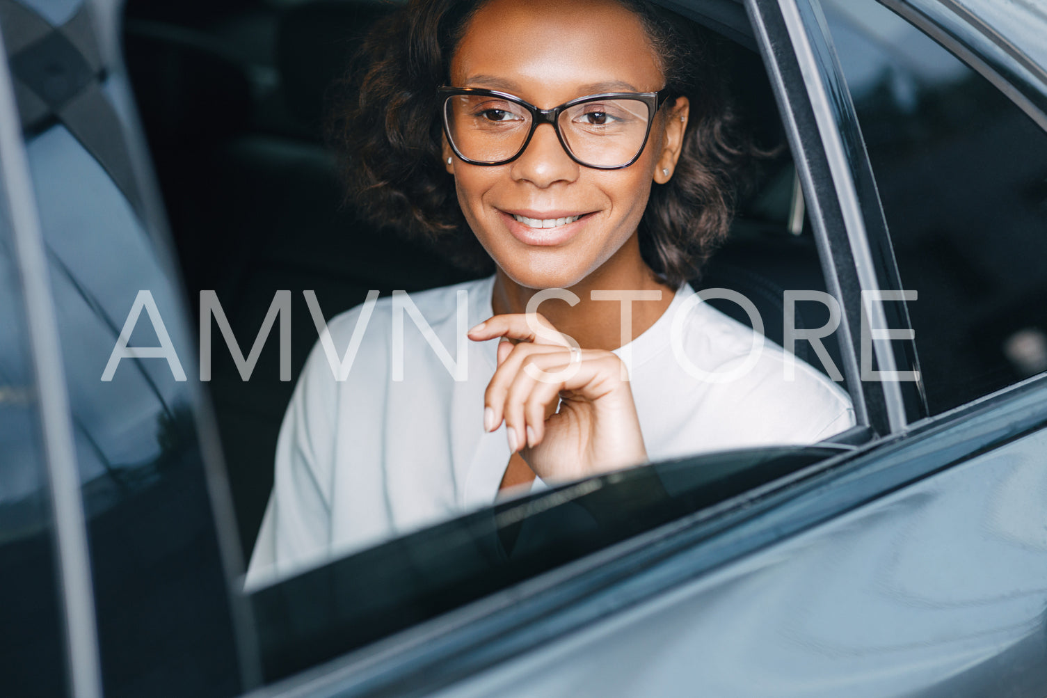 Smiling businesswoman sitting on a backseat of the taxi and looking away. Young entrepreneur in a car.	