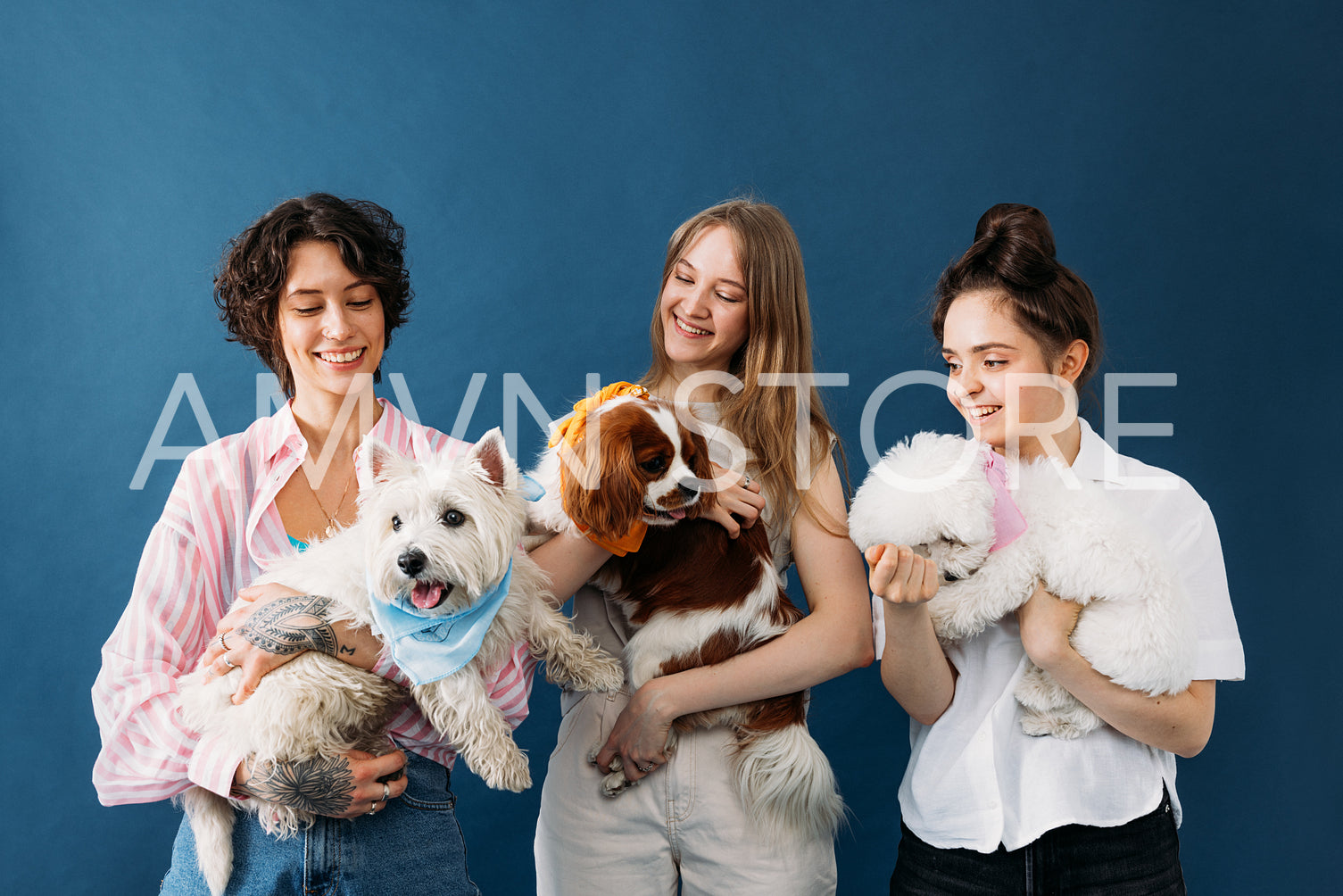 Three smiling pet owners holding their little cute dogs while st