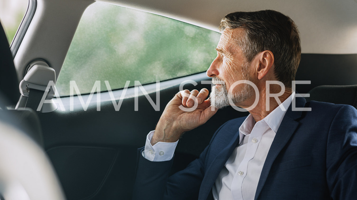 Side view of mature businessman sitting on a backseat of a car and looking out of window	