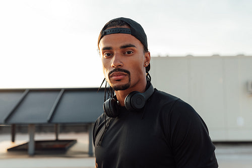 Close-up portrait of a young male athlete wearing a cap and wireless headphones