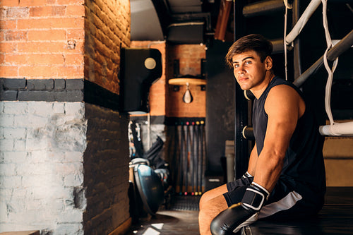 Side view of a young boxer sitting in gym