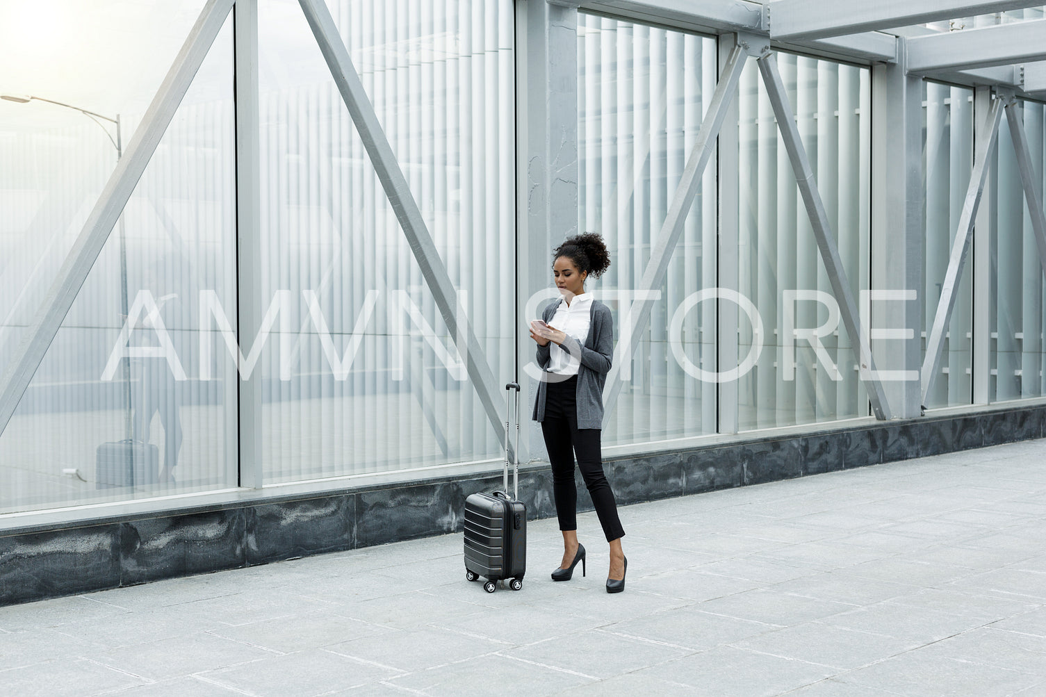 Businesswoman standing in airport terminal, checking mobile phone	