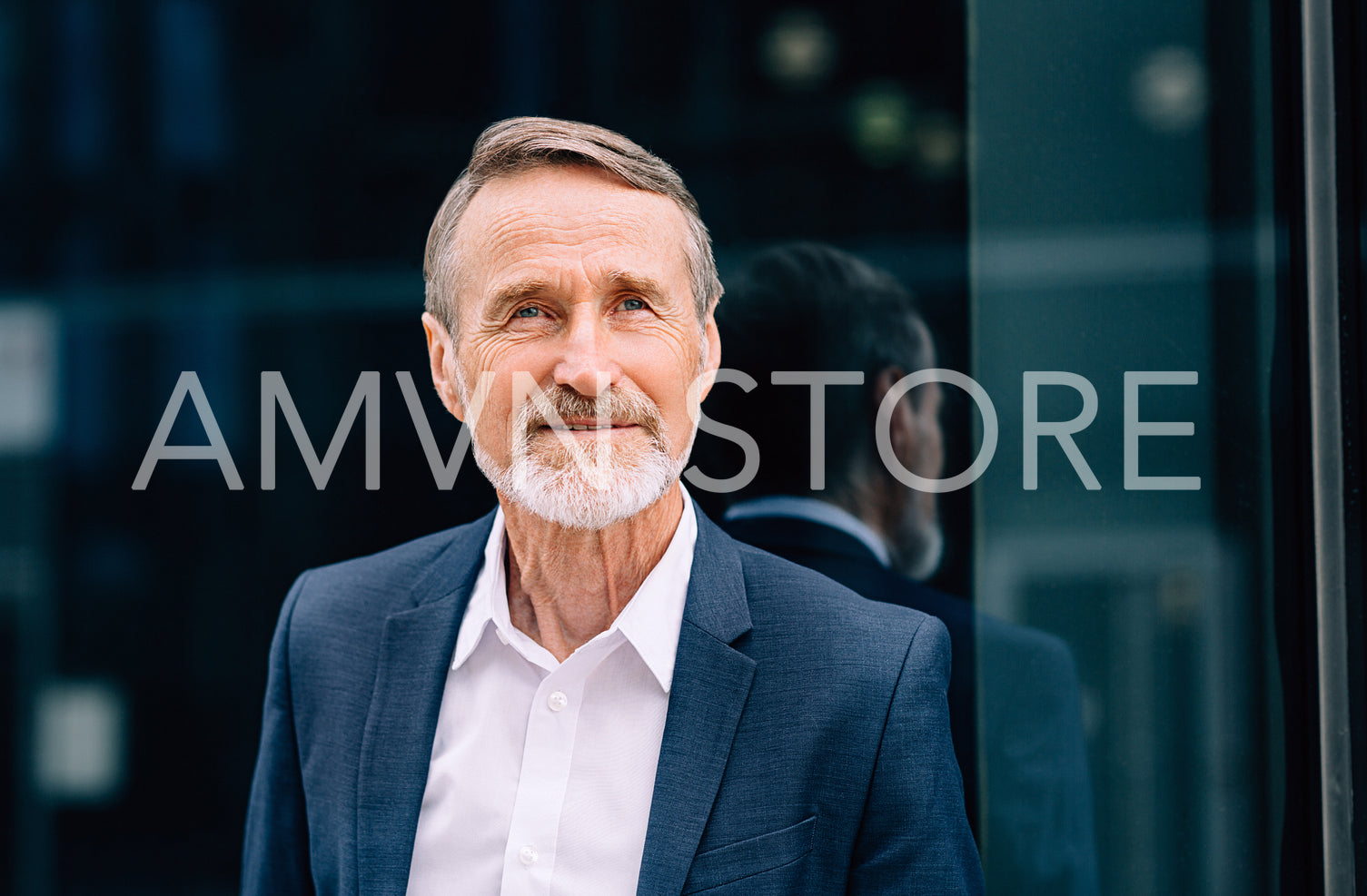 Portrait of a bearded businessman standing at glass front and looking away