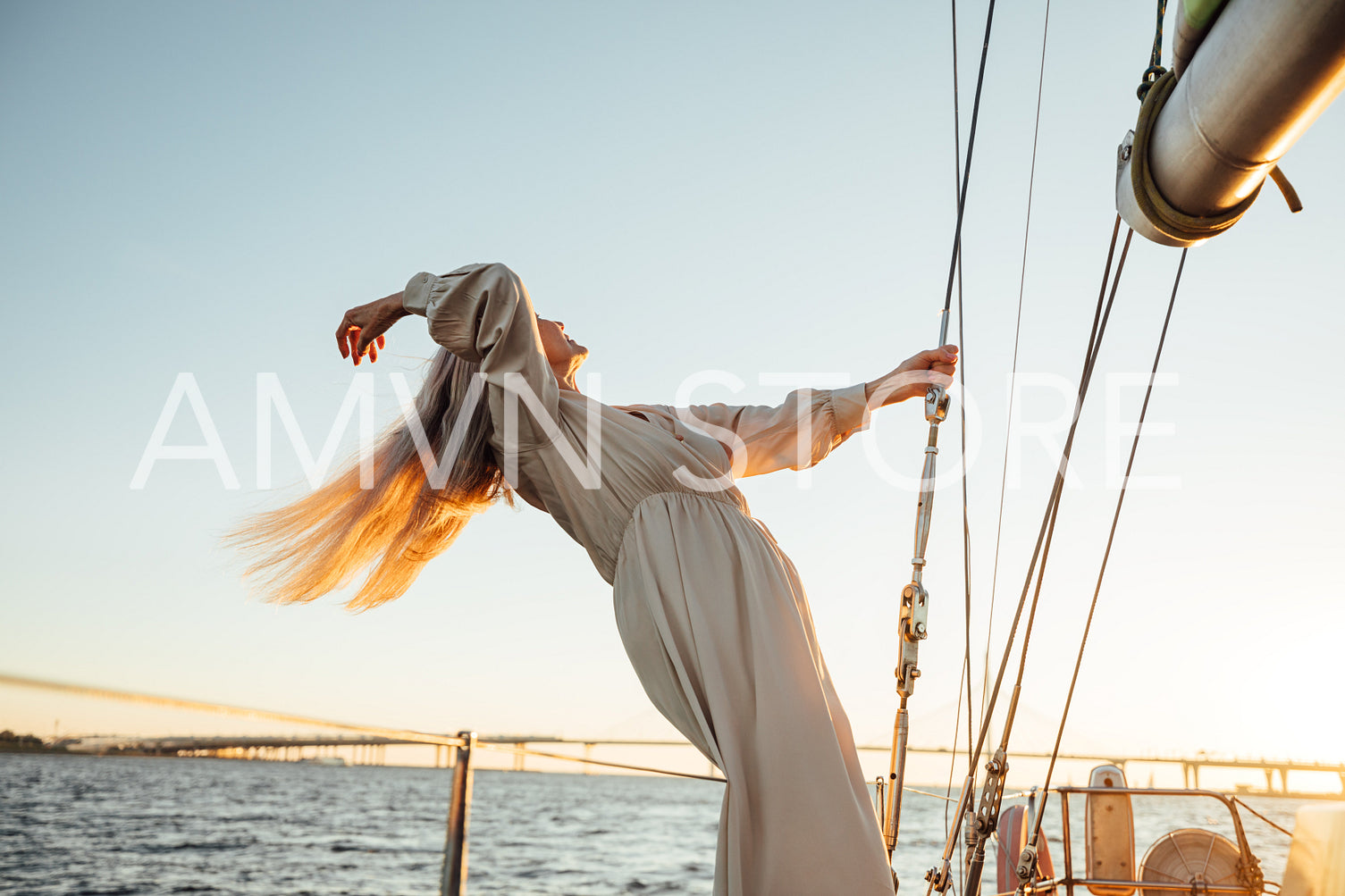 Elegant mature woman with long hair standing on a private yacht and enjoying a sunset	