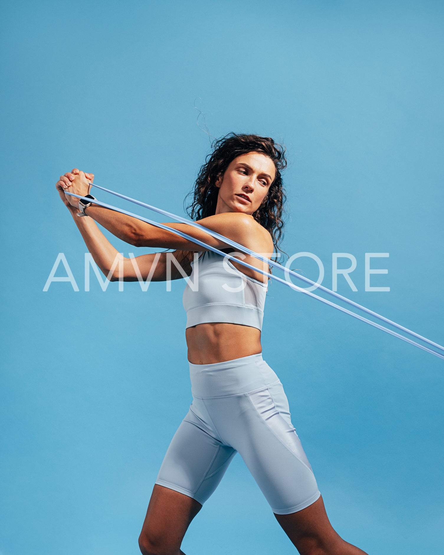 Woman in blue sportswear doing exercising with stretching band in studio