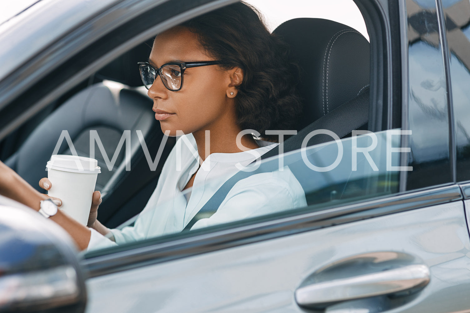 Businesswoman sitting in car. Side view of female driver holding a coffee.	