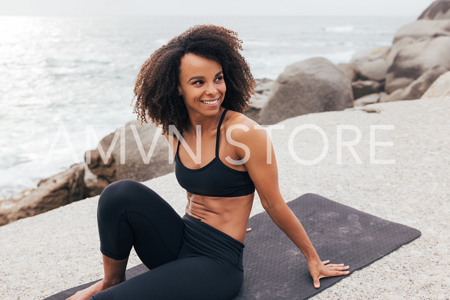 Fit woman on a mat at ocean. Slim female relaxing after yoga exercises.