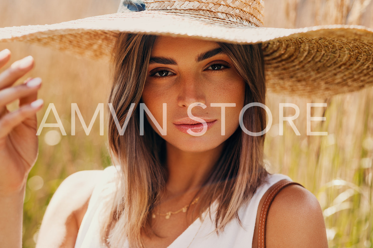 Beautiful woman in straw hat posing on a field and looking at camera	