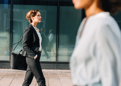 Businesswoman commuting to the office carrying her bag. Woman in formalwear walking outdoors.