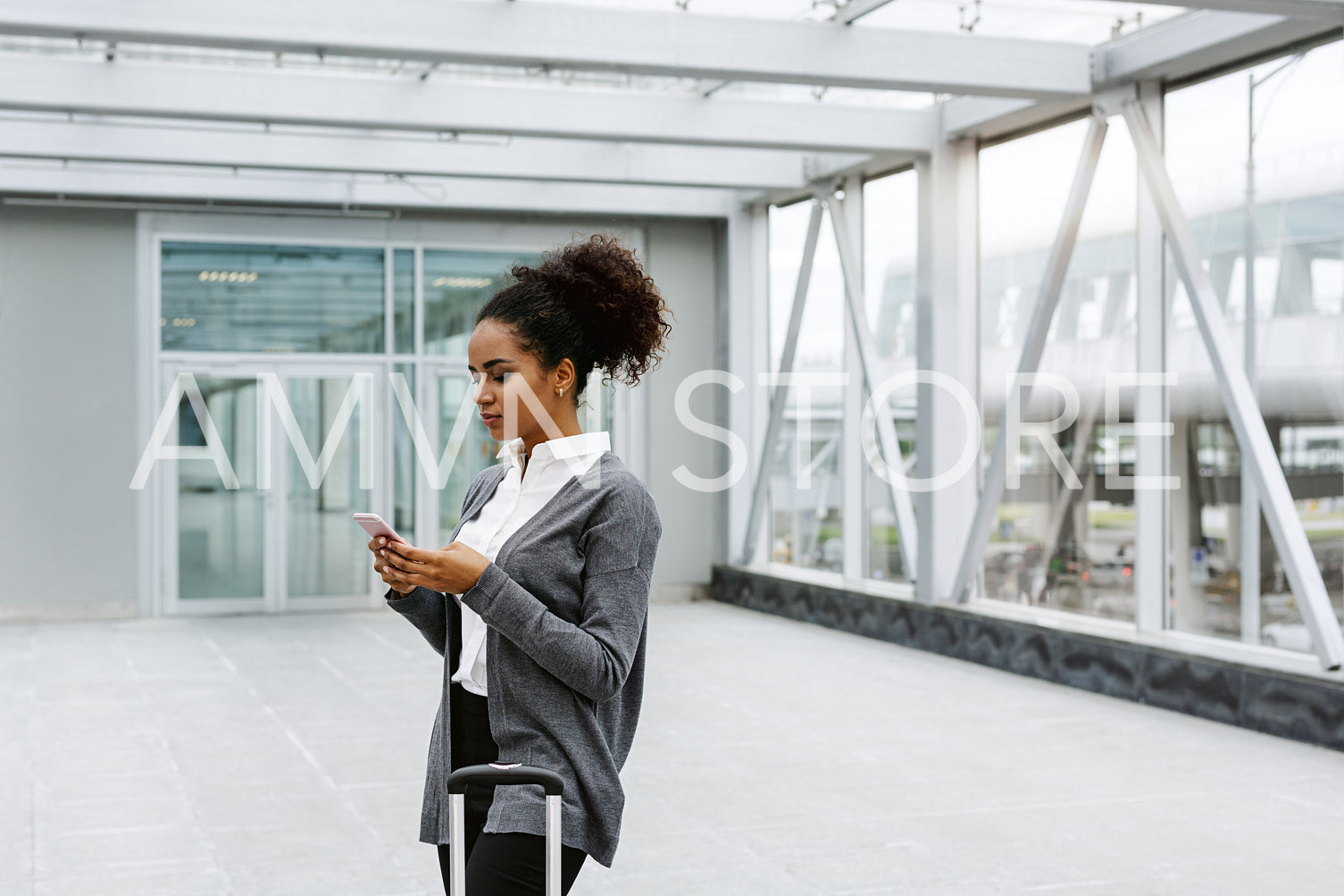 Young businesswoman waiting in airport terminal, checking mobile phone	