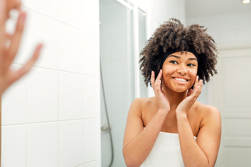 Happy woman touching her face in bathroom