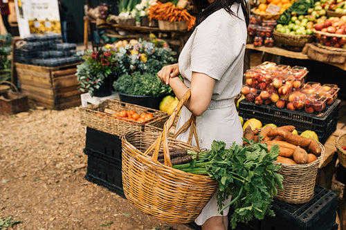 Woman with a basket in her hand at an outdoor market. Unrecognizable female looking for organic food on local farmer market.