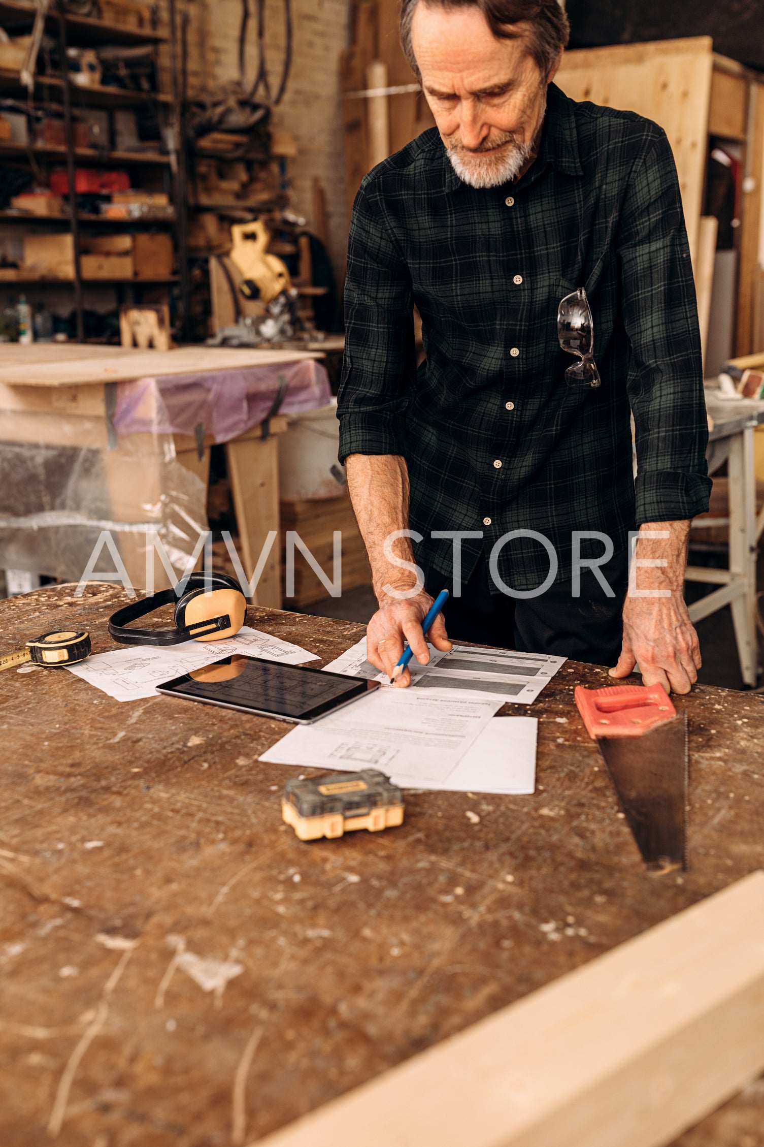 Mature man checking drawing before starting his work at a carpentry workshop	