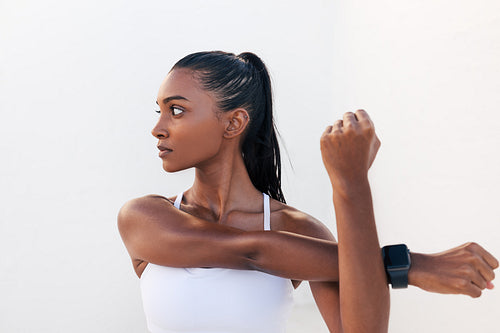 Young woman flexing her hands and looking away. Female stretching and warming up her hands before a workout.